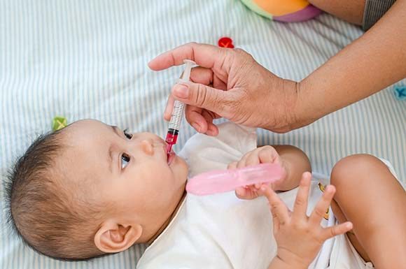 Barn får vaccin i munnen.