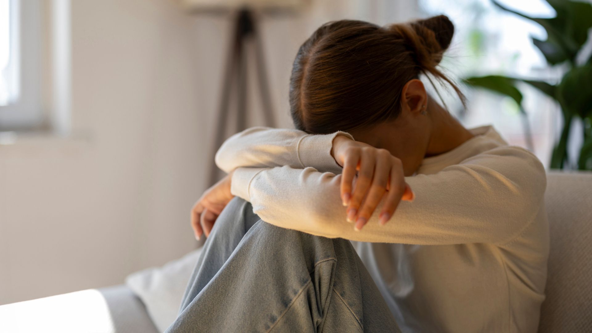 Flicka i tonåren som sitter i soffa, är ledsen