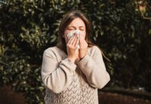 Nationella riktlinjer för allergivård fastställda för första gången En person med allergi, ståendes utomhus i beige tröja och snyter sig