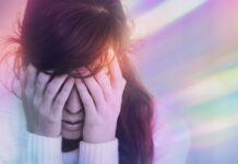 Epilepsiläkemedel kopplas till färre dagar med migränaura En person håller för ögonen med ljussken i olika färger som omger den för att illustrera migränaura.