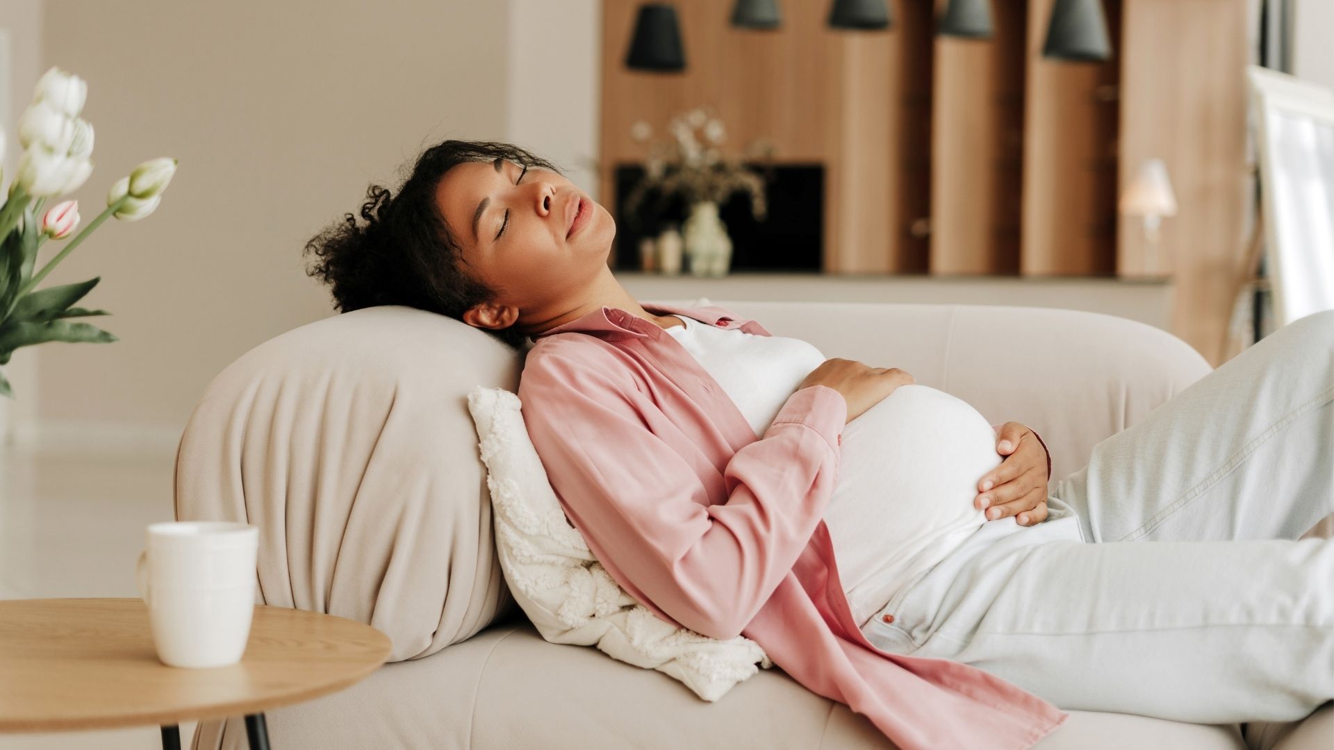Gravid kvinna ligger på en soffa.